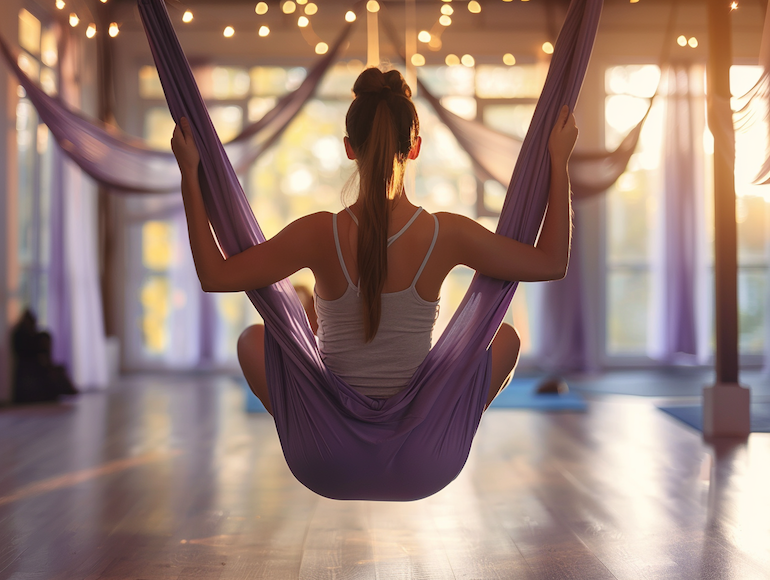 Dona en una classe d'aeroioga en una hamaca lila