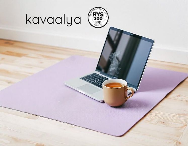 Esterilla de ioga amb portàtil i tassa de te, ideal per a una formació de ioga online des de casa.